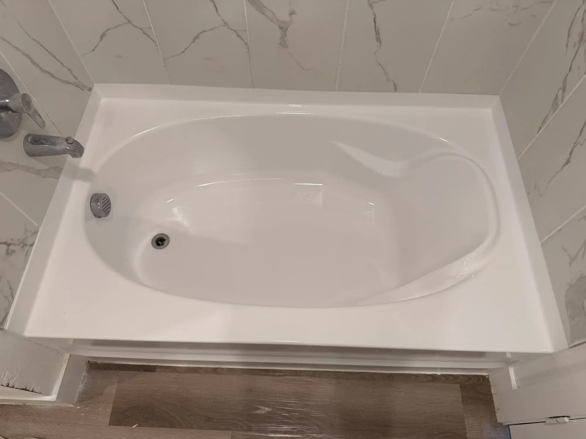 Bañera oval reesmaltada junto a azulejo de mármol